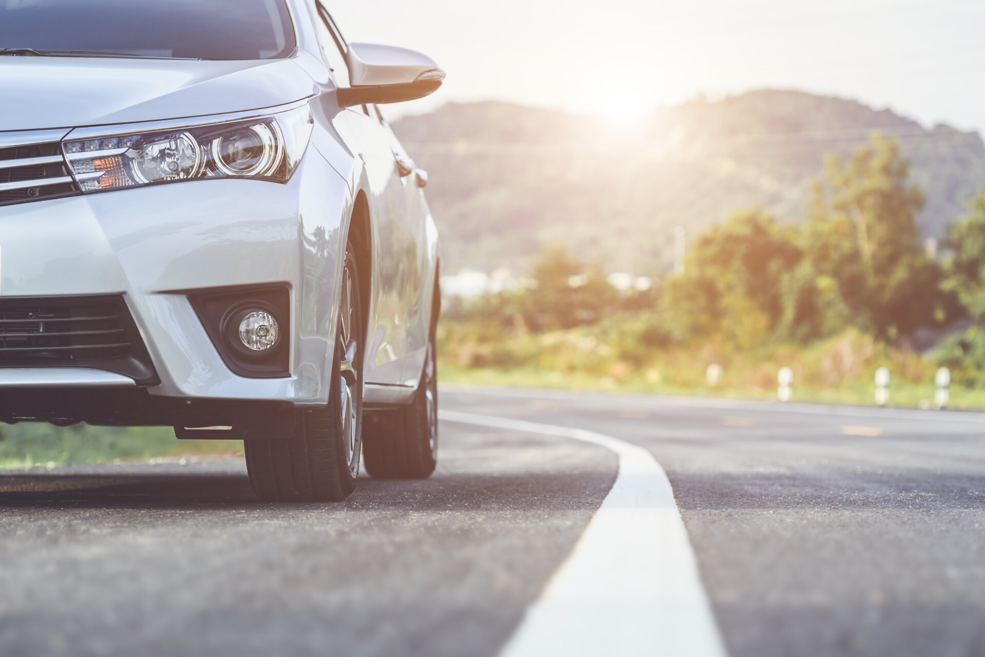 Recorte da metade da frente de um carro andando em uma estrada de asfalto