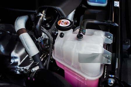 o sistema de arrefecimento de um carro está em foco, com o líquido de arrefecimento na cor rosa