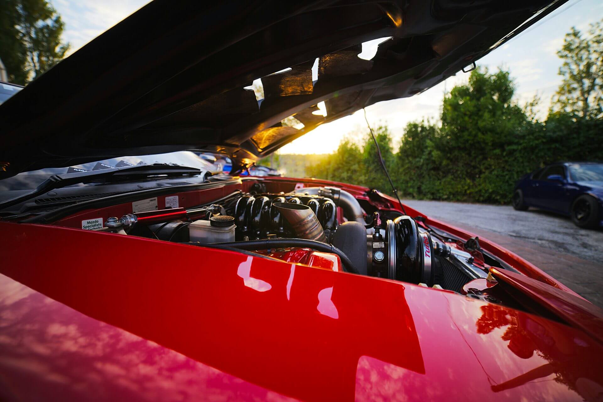 Carro vermelho com o capô aberto.