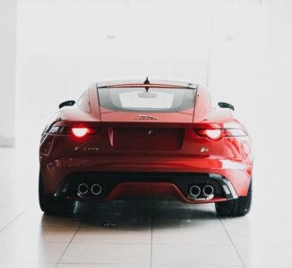 Vista traseira de um carro esportivo vermelho em um showroom, destacando a importância da regulagem do farol para manter a visibilidade e segurança ao dirigir.