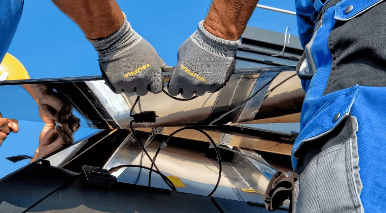 Instalação de um sistema fotovoltaico por um técnico usando luvas de segurança, detalhe das mãos conectando cabos em painéis solares sob luz solar intensa.