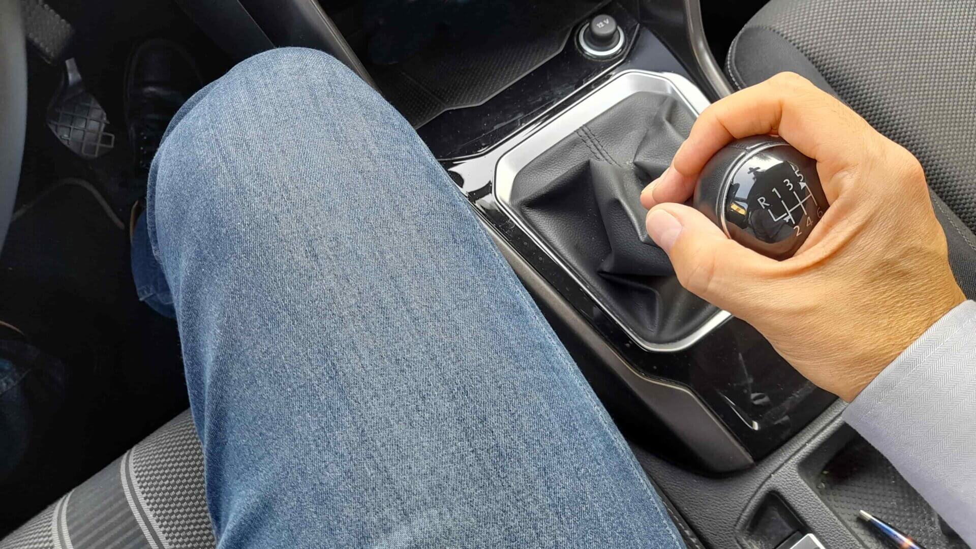 Mão está em destaque trocando a marcha do carro.