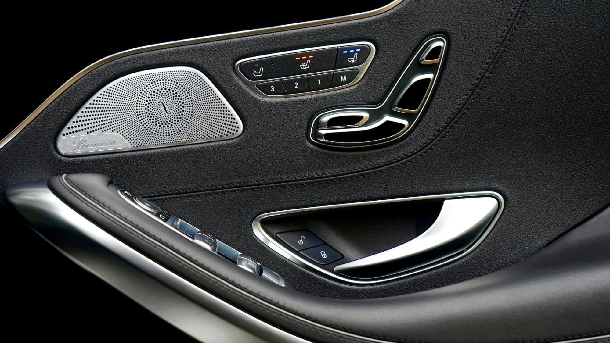 o interior da porta de um  carro preto com detalhes em prata, com foco nos botões de sistemas eletrônicos 