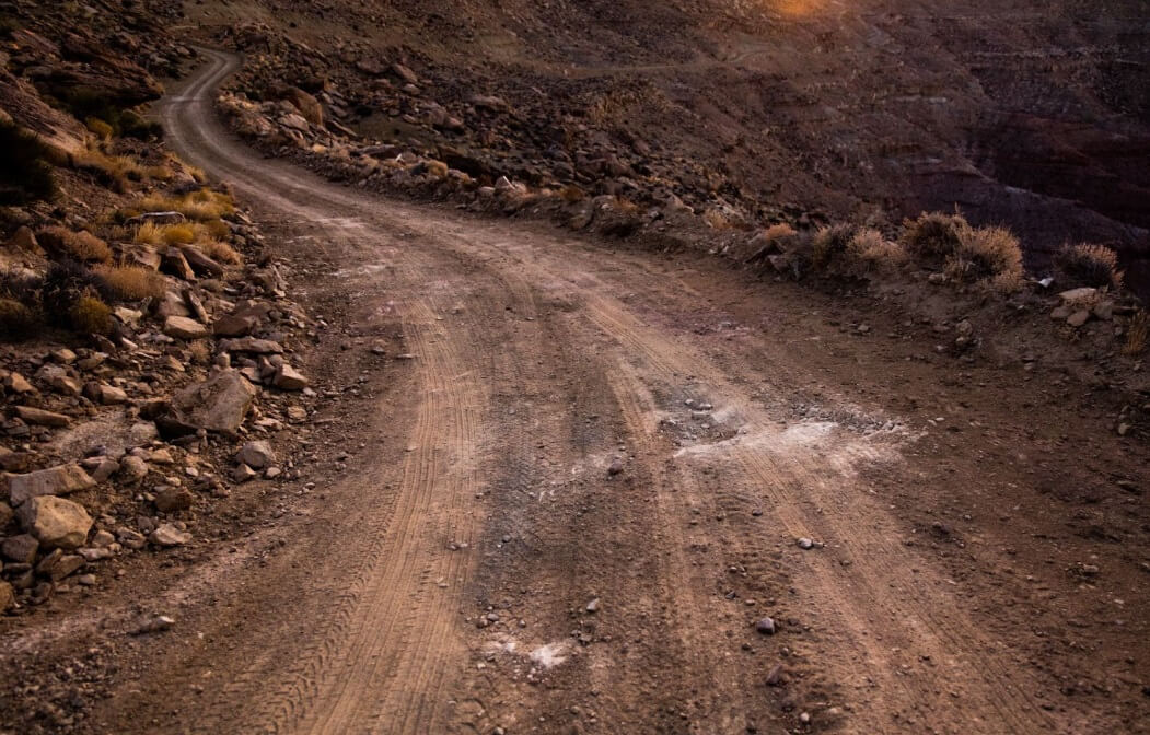 Estrada de terra acidentada, cenário que exemplifica a importância de entender para que serve a bieleta na absorção de impactos e estabilidade do veículo.