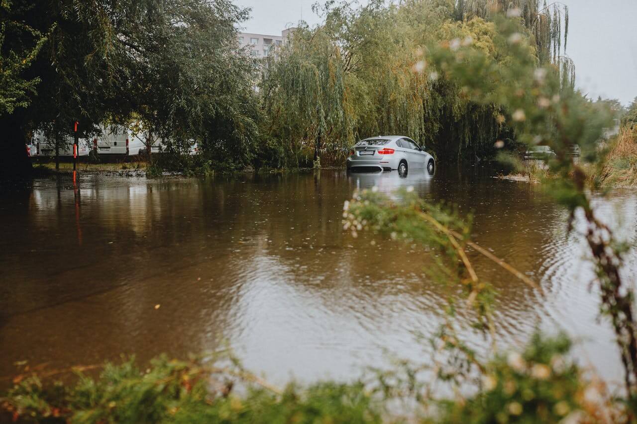 Carro passando por um trecho alagado, enfatizando a importância de se dirigir com cuidado em alagamentos pelo risco de aquaplanagem. 