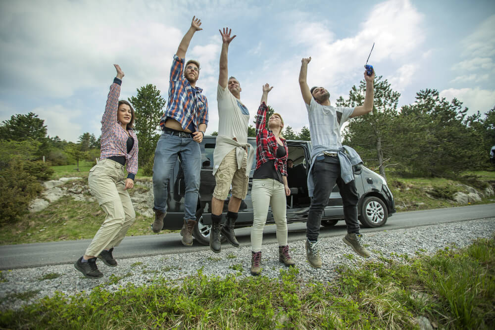 Imagem de pessoas celebrando ao lado de fora de um carro