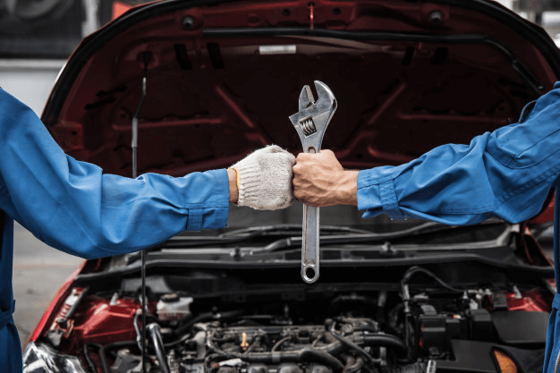 Imagem dos braços de dois mecânicos que sabem das melhores baterias de carro para seus clientes