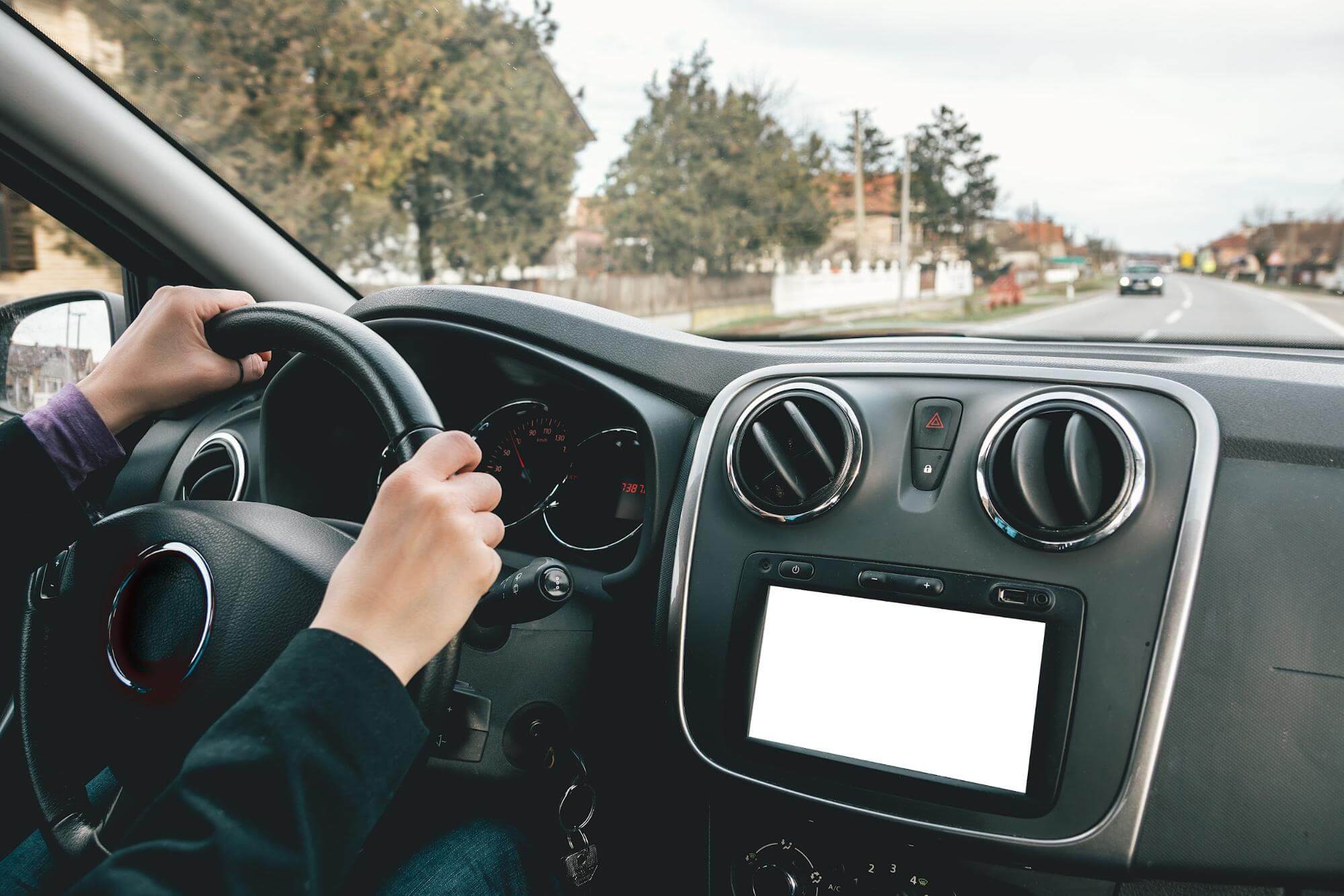 o interior de um veículo e seu painel são o foco da imagem,onde também é possível identificar mão femininas segurando o volante