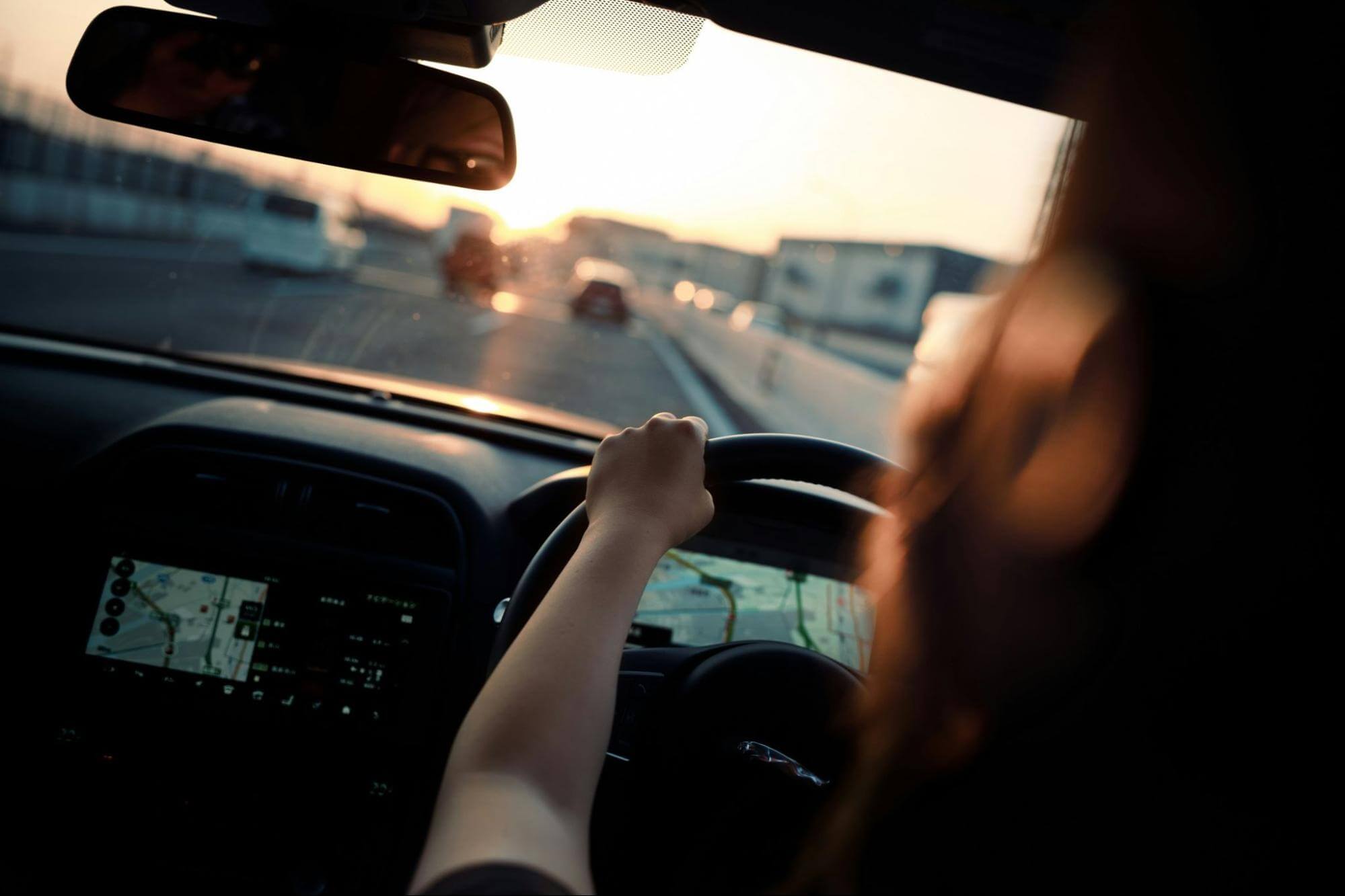uma pessoa está dirigindo no pôr-do-sol em uma estrada