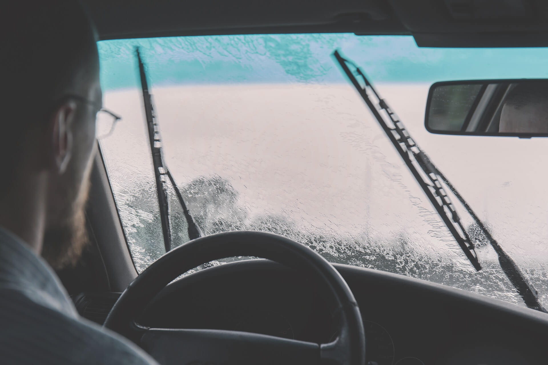 um homem está dirigindo um veículo em meio à chuva após realizar a cristalização dos vidros