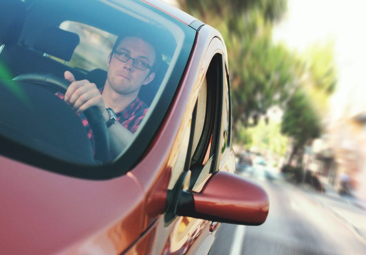 Homem dirigindo carro enfatizando que é necessário realizar a baliza para tirar a carteira de motorista.