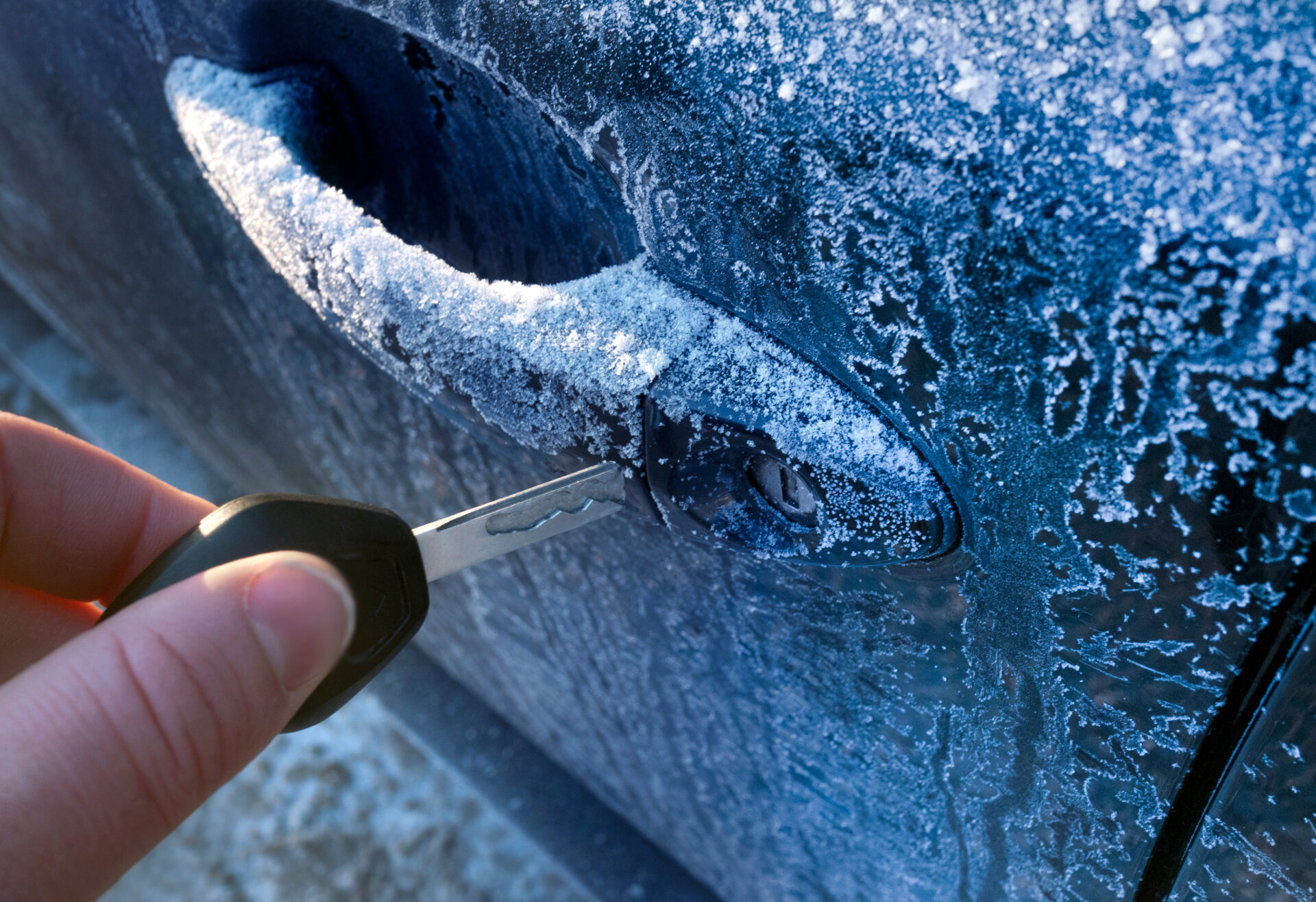 Pessoa colocando a chave de carro em um veículo congelado.