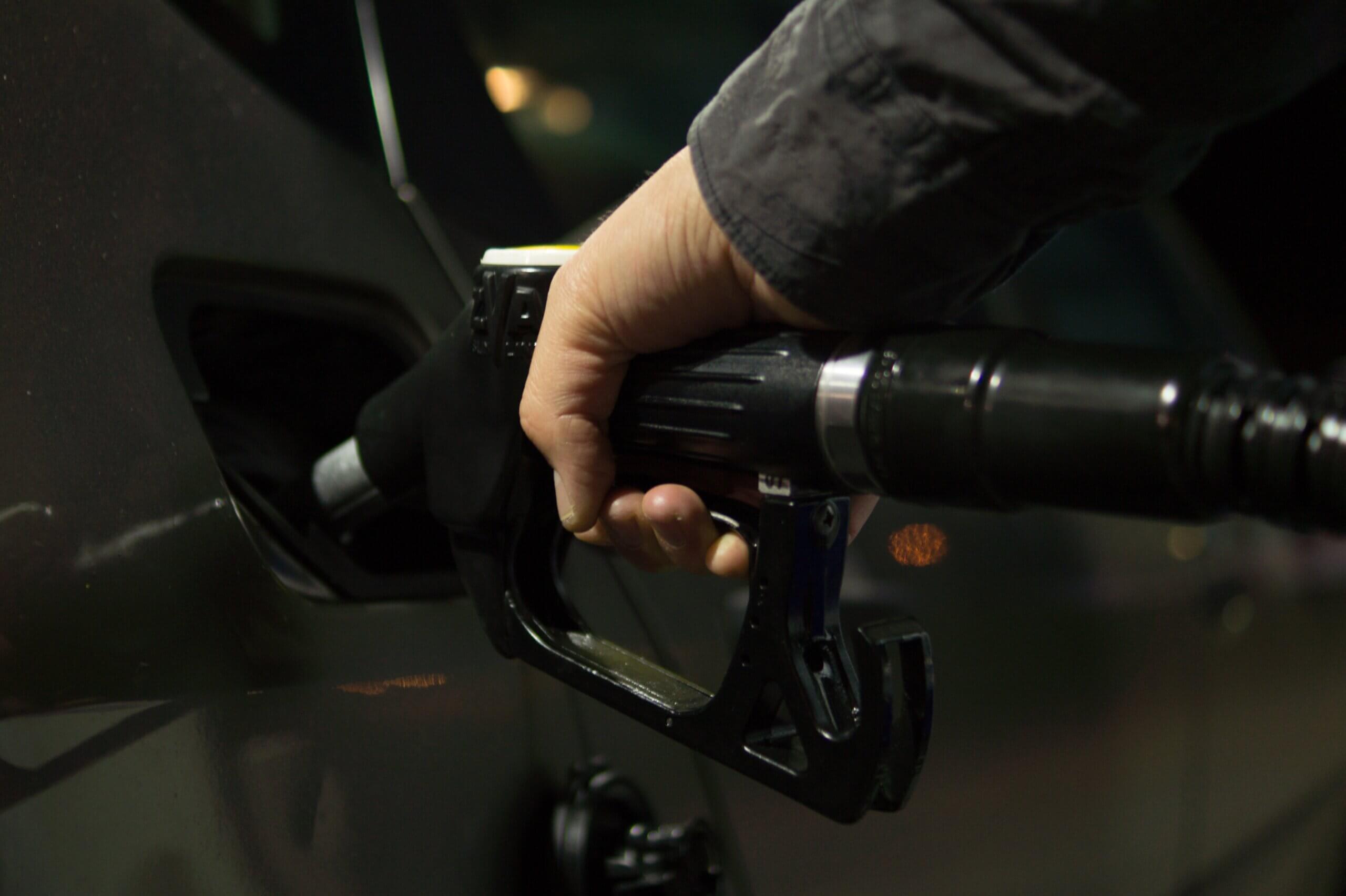uma mangueira de combustível está sendo segurada dentro do tanque do veículo por uma mão masculina