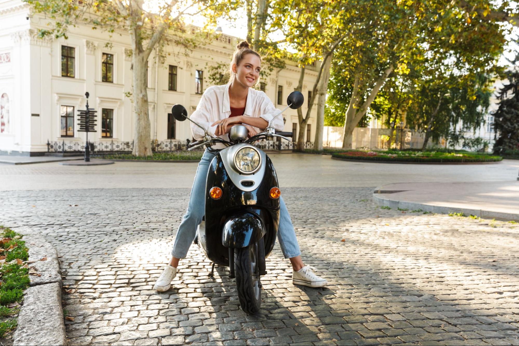 uma mulher está dirigindo uma scooter em uma praça