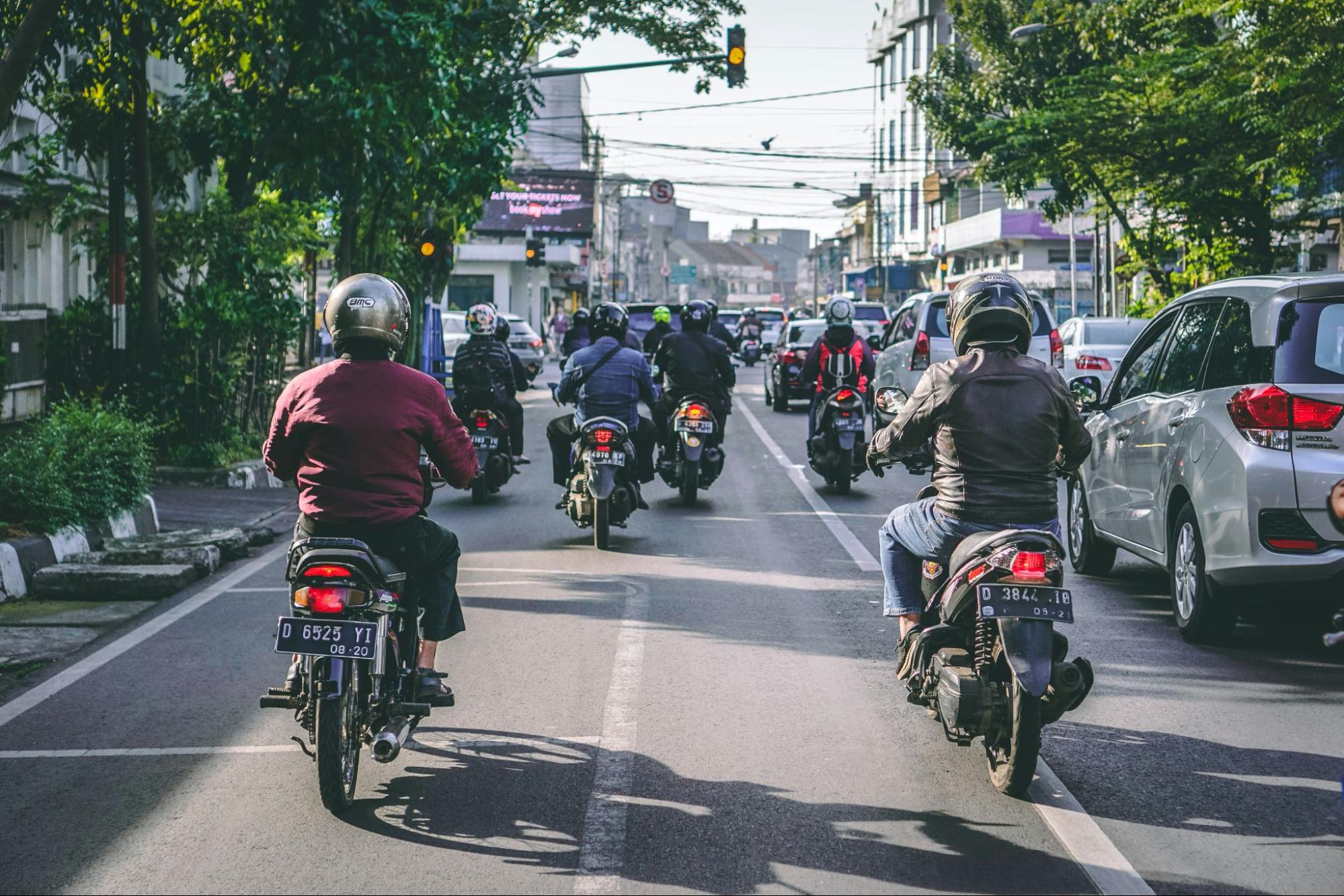 diversos motoristas de motos estão dirigindo pela rua de uma cidade