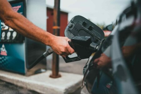 Mão de um homem abastecendo um carro com GNV (Gás Natural Veicular), evidenciando uma alternativa mais ecológica e econômica aos combustíveis tradicionais. 