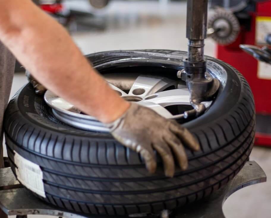 Profissional substituindo um pneu utilizando uma máquina de montagem de pneus em uma oficina mecânica.