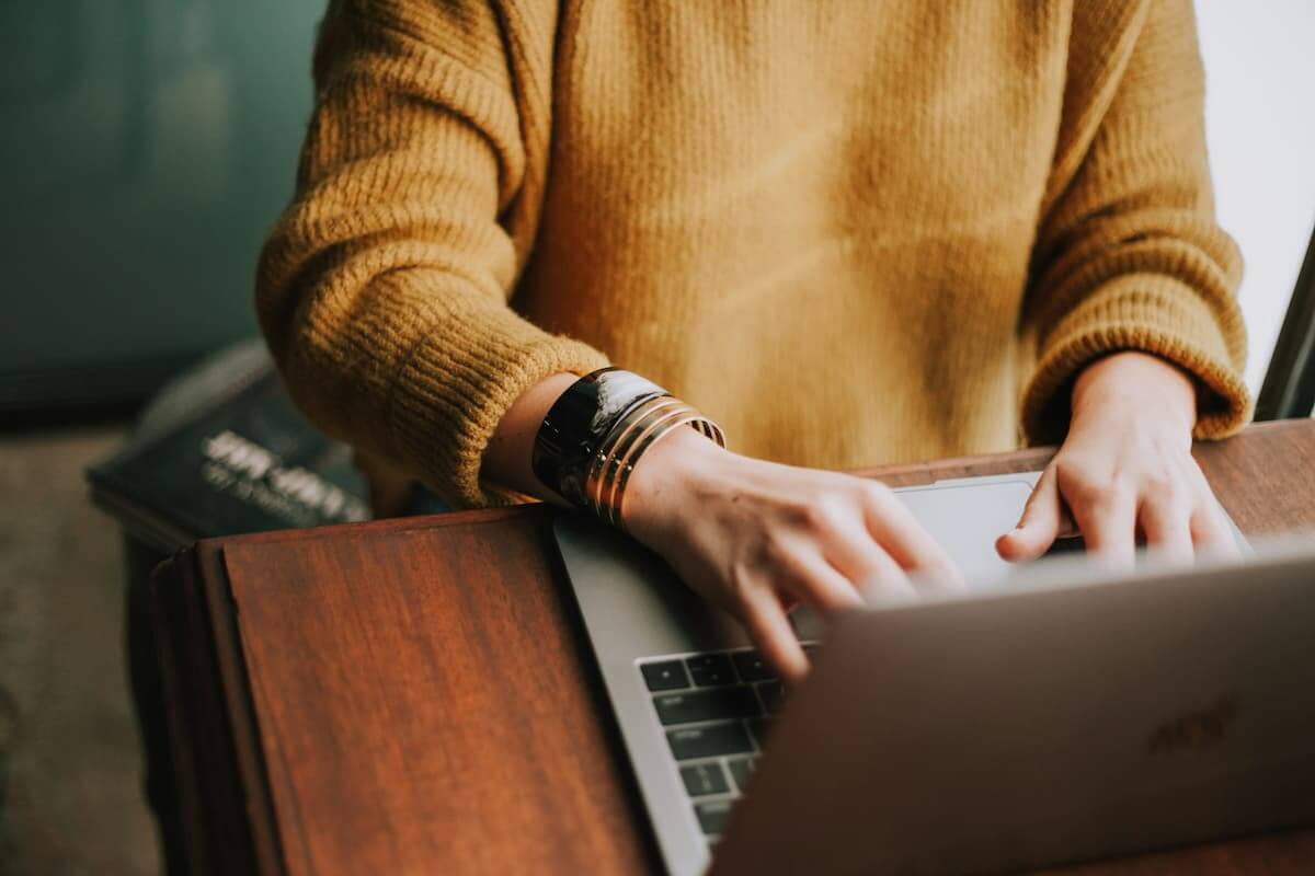 Como renovar carteira de motorista: Mãos de uma pessoa digitando em um laptop, representando a renovação da carteira de habilitação pela internet.