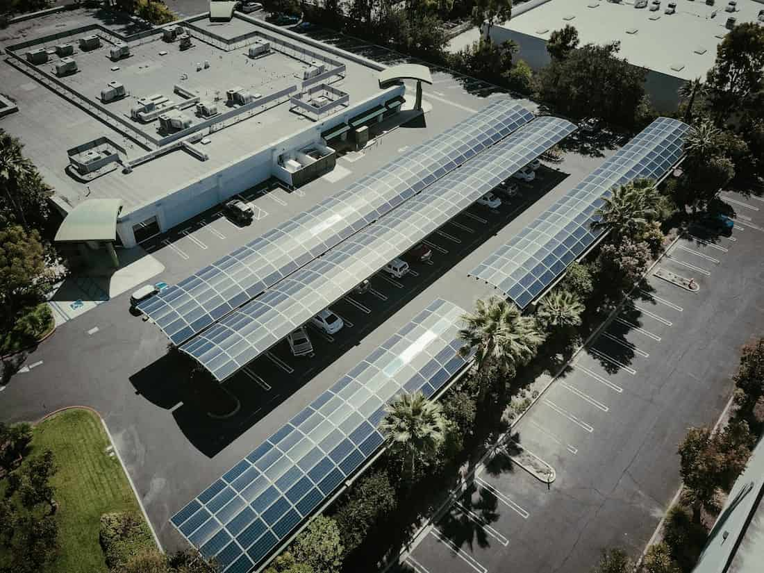 Vista aérea de um estacionamento coberto por painéis solares conectados à rede elétrica em um centro urbano, mostrando a aplicação prática do sistema on-grid.