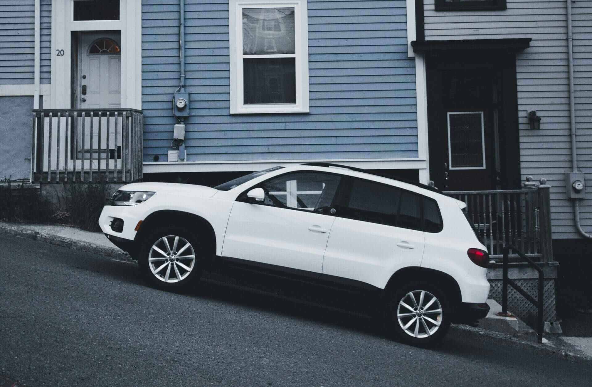 Carro branco estacionado em uma rua íngreme.