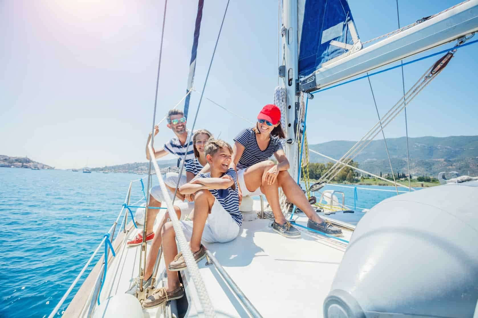 Família sorrindo e se divertindo a bordo de um barco à vela em um dia ensolarado.