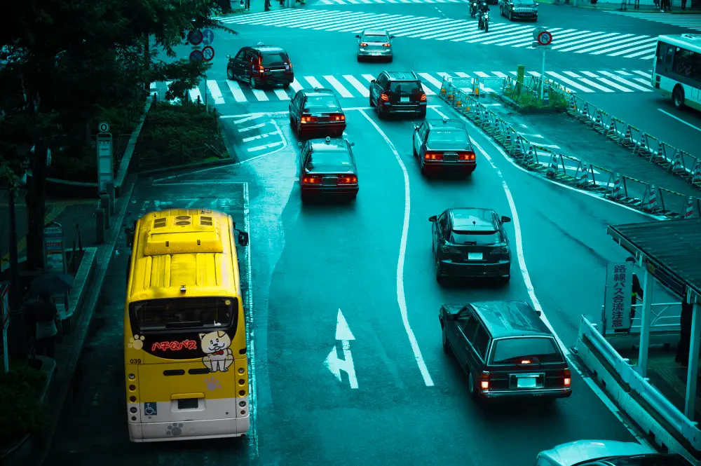 Cruzamento urbano com vários carros e um ônibus, destacando a sinalização de trânsito.