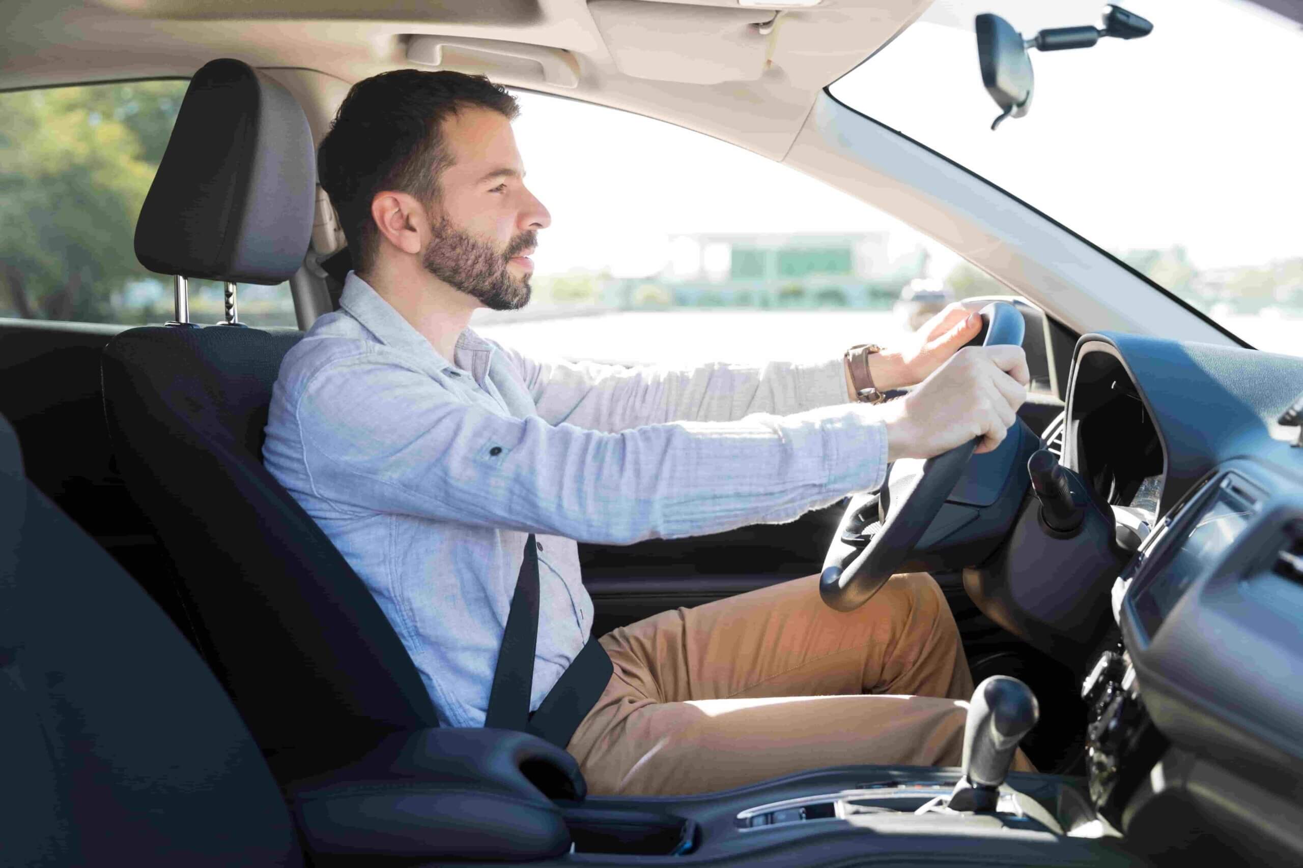 Homem de camisa social dirigindo um carro.