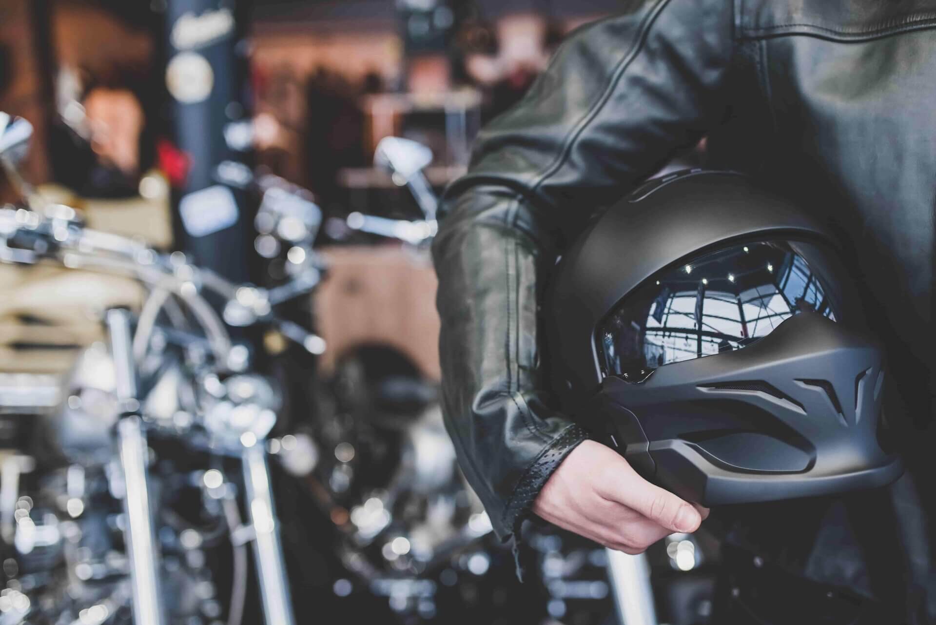Pessoa segurando um capacete preto de moto.