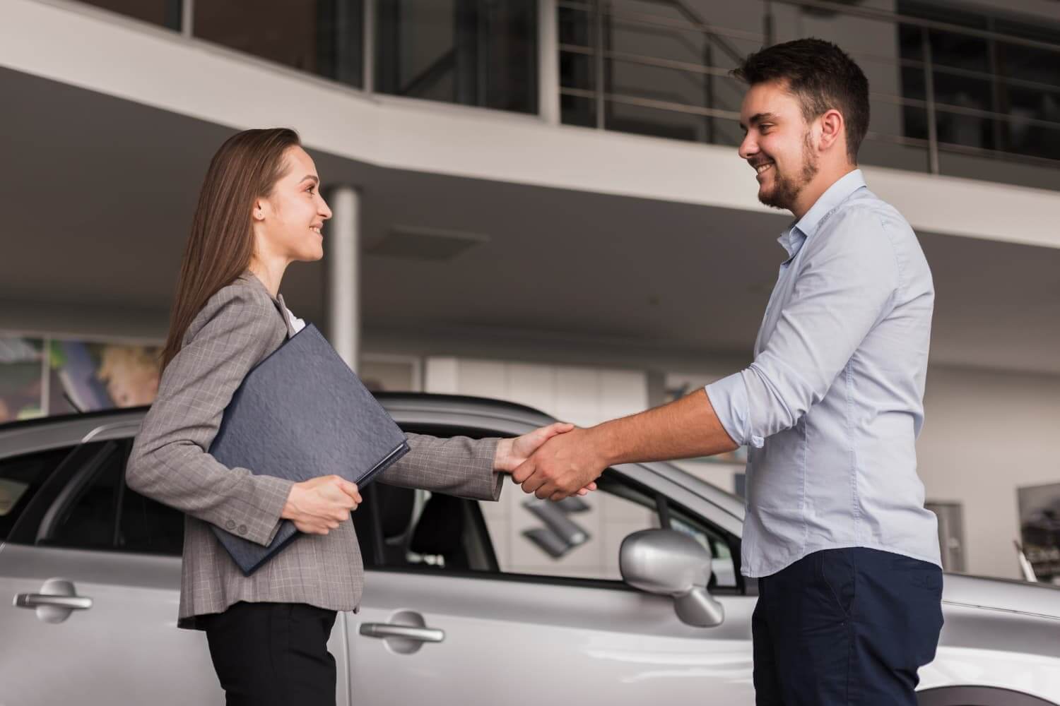 Pessoas apertando as mãos diante de um carro branco.