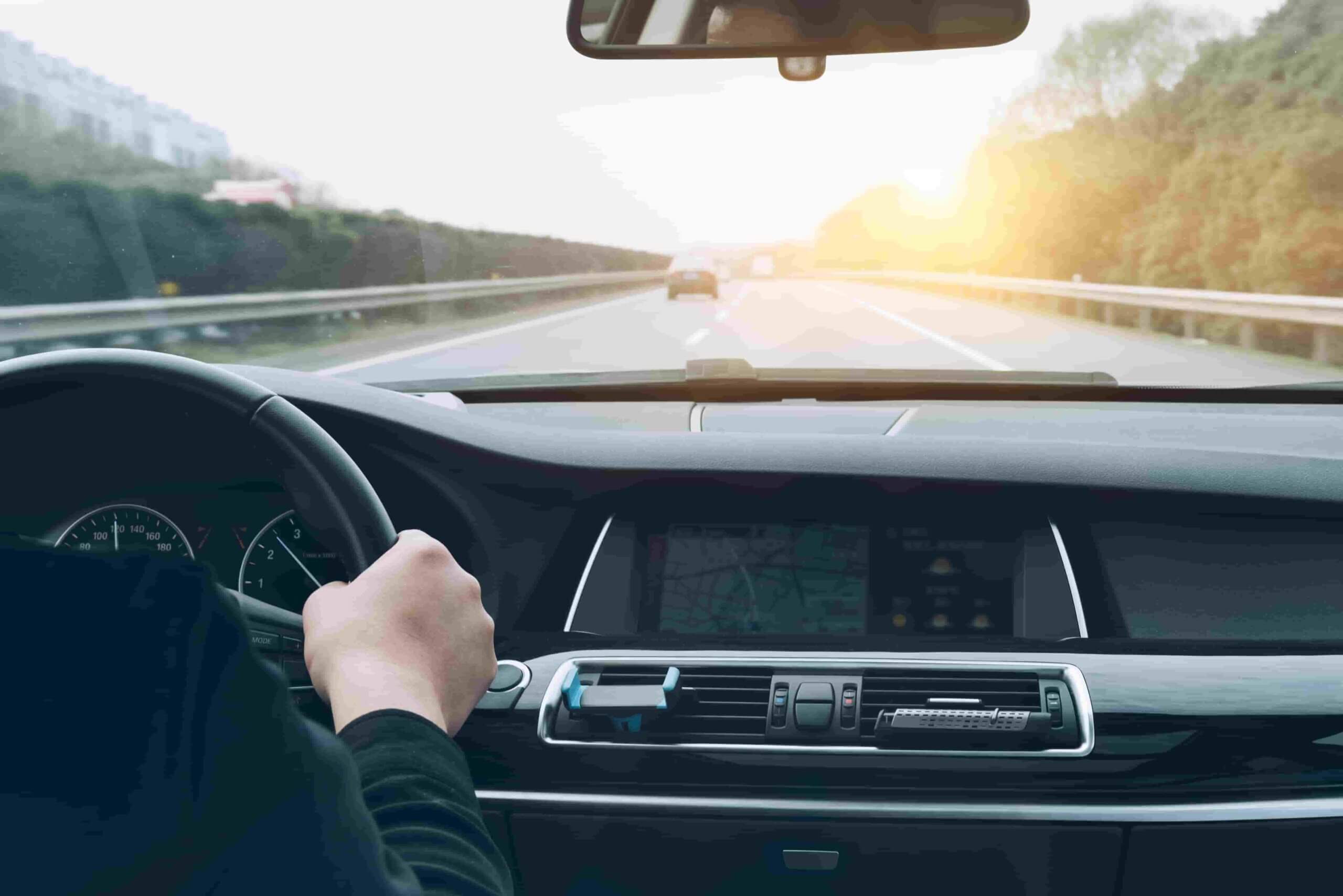 Pessoa dirigindo um carro com o painel e o GPS visíveis.