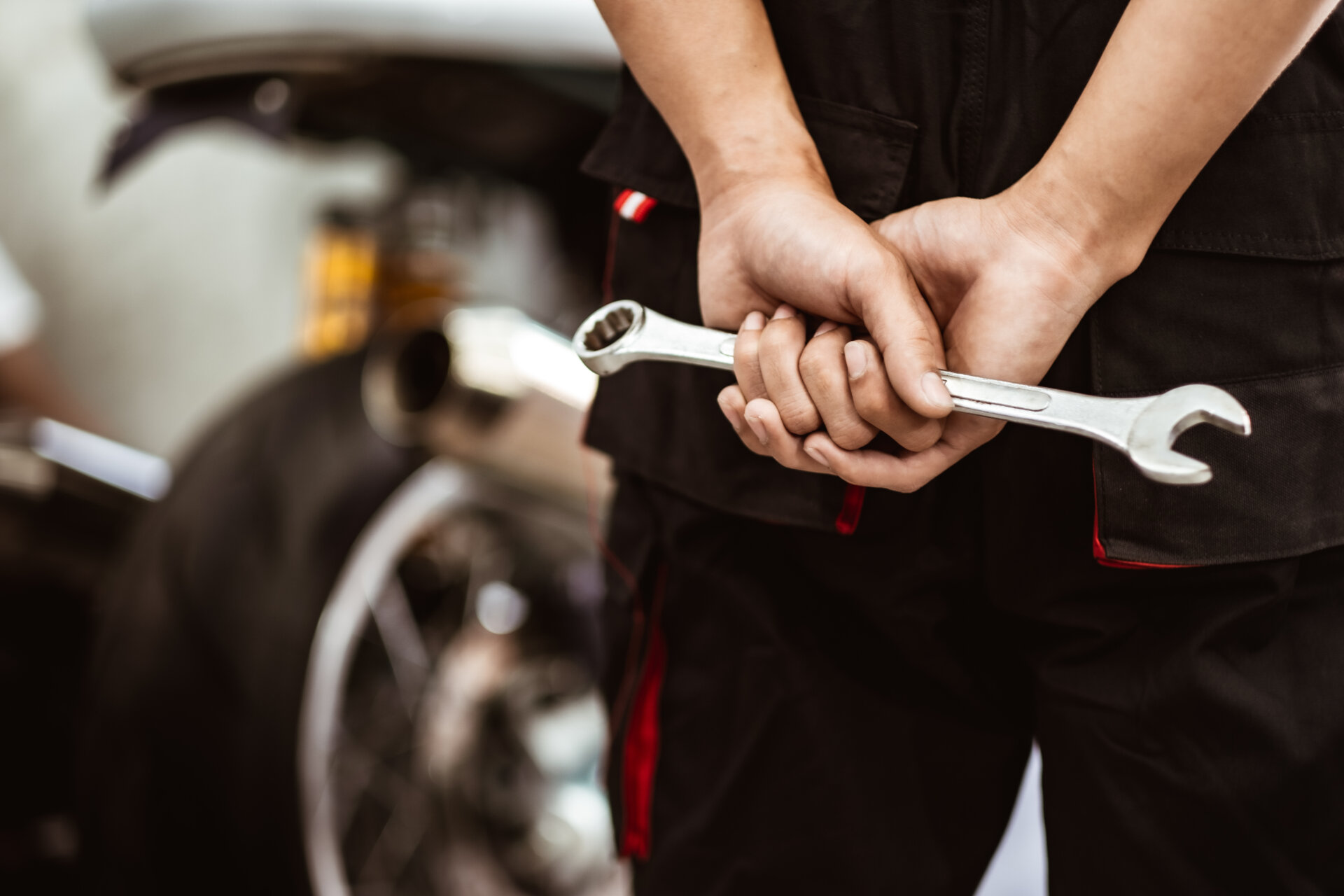 Mecânico de costas segurando uma chave de fenda prateada.