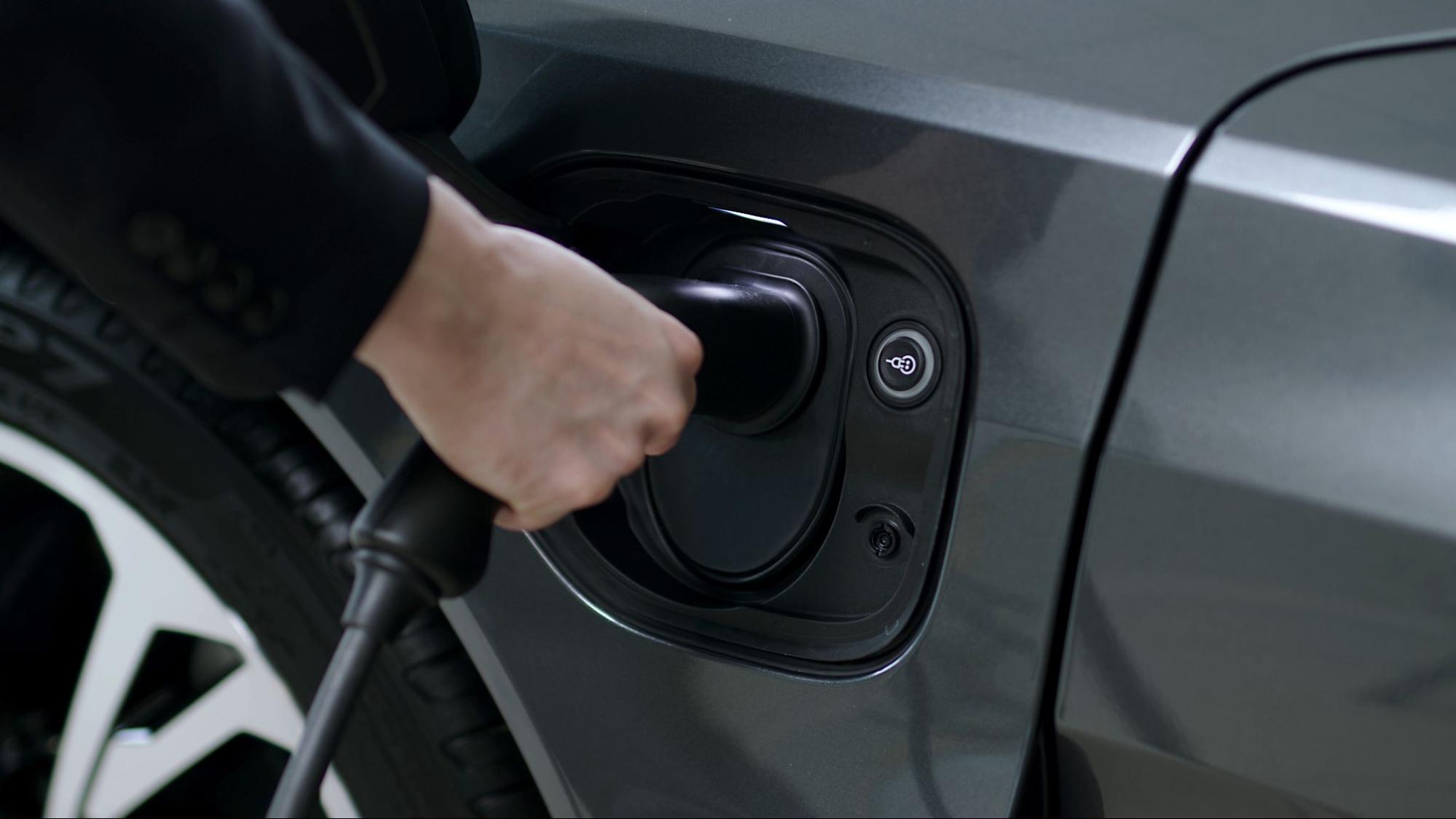 Pessoa encaixando carregador de carro elétrico no veículo