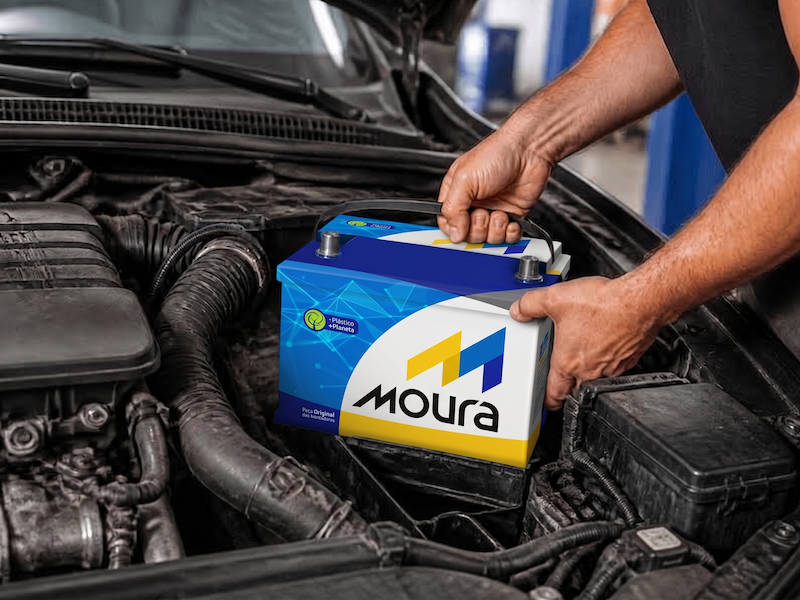  Homem retira uma bateria Moura do motor de um carro.