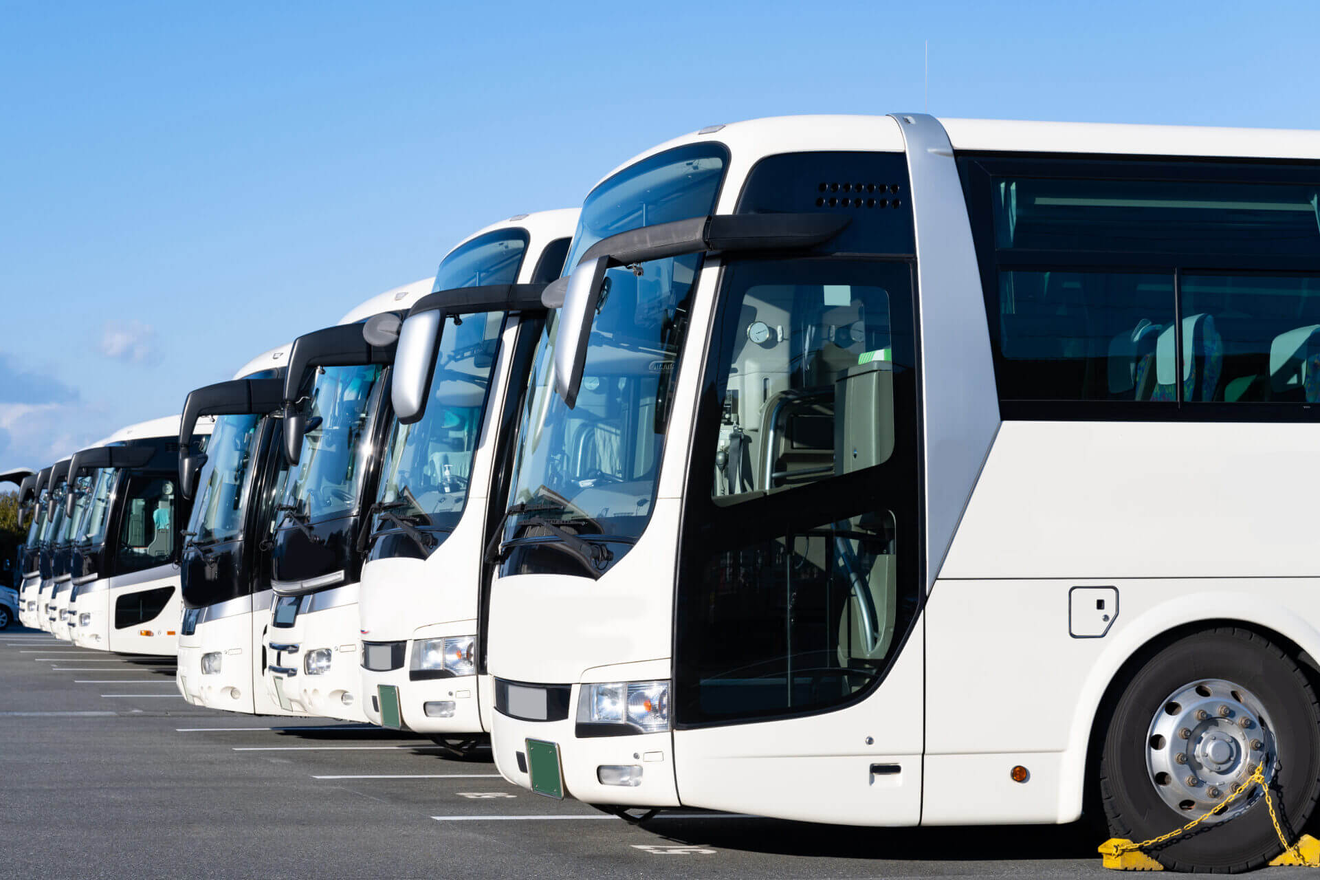 Frota de ônibus brancos estacionados em pátio aberto