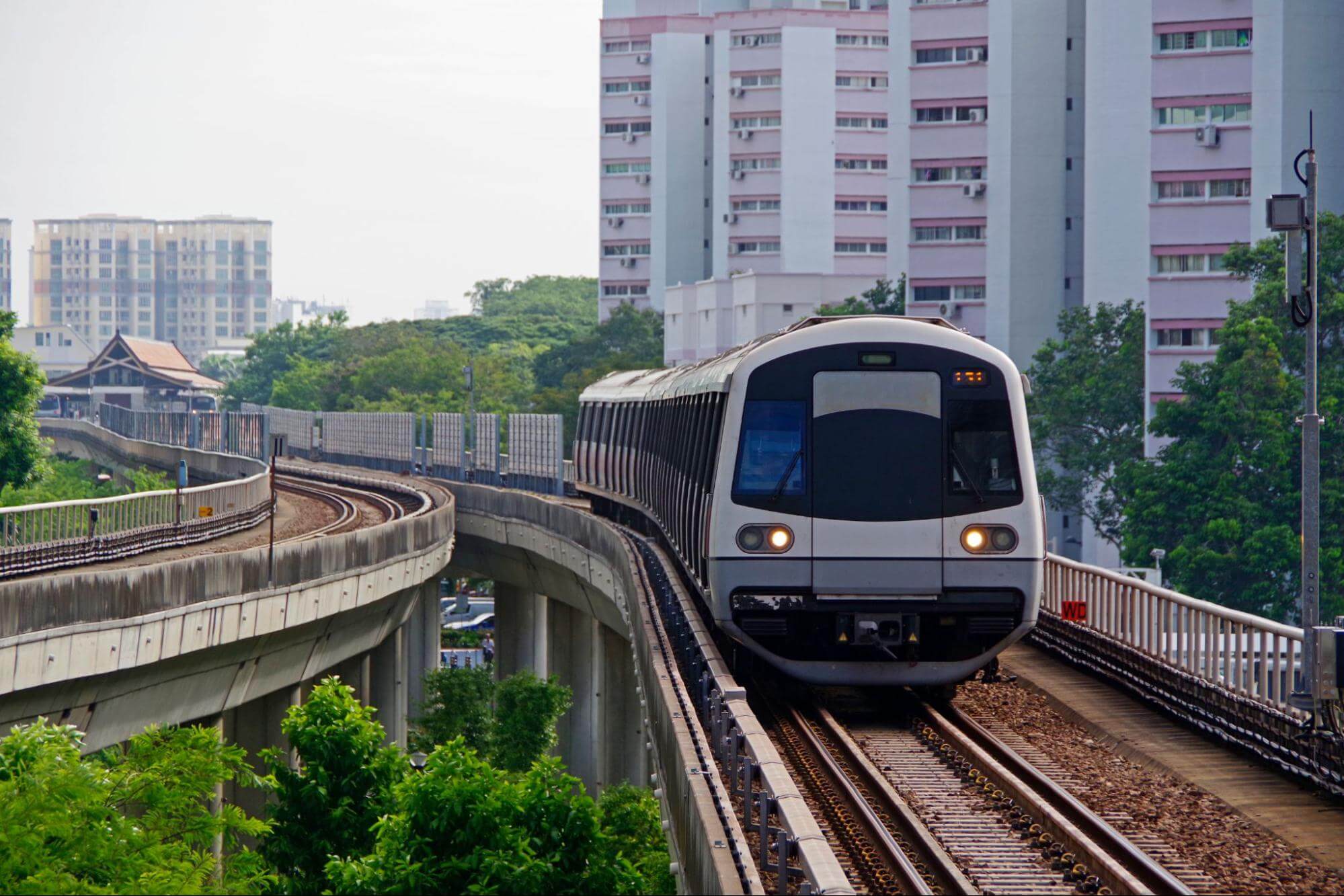 Trem sobre trilhos com prédios ao fundo.