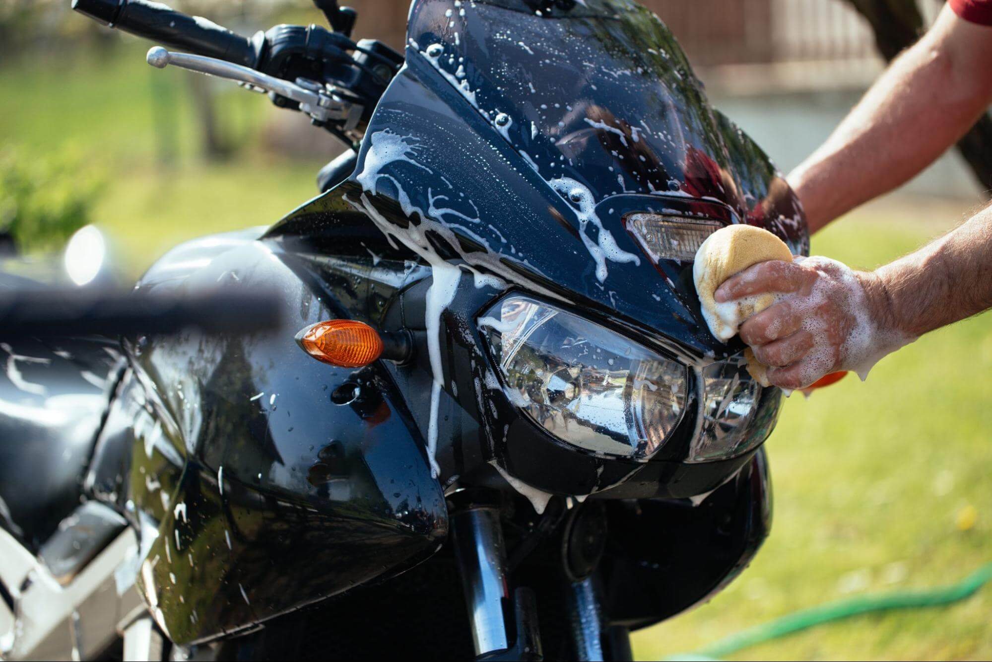 Pessoa segurando uma esponja enquanto lava sua moto preta