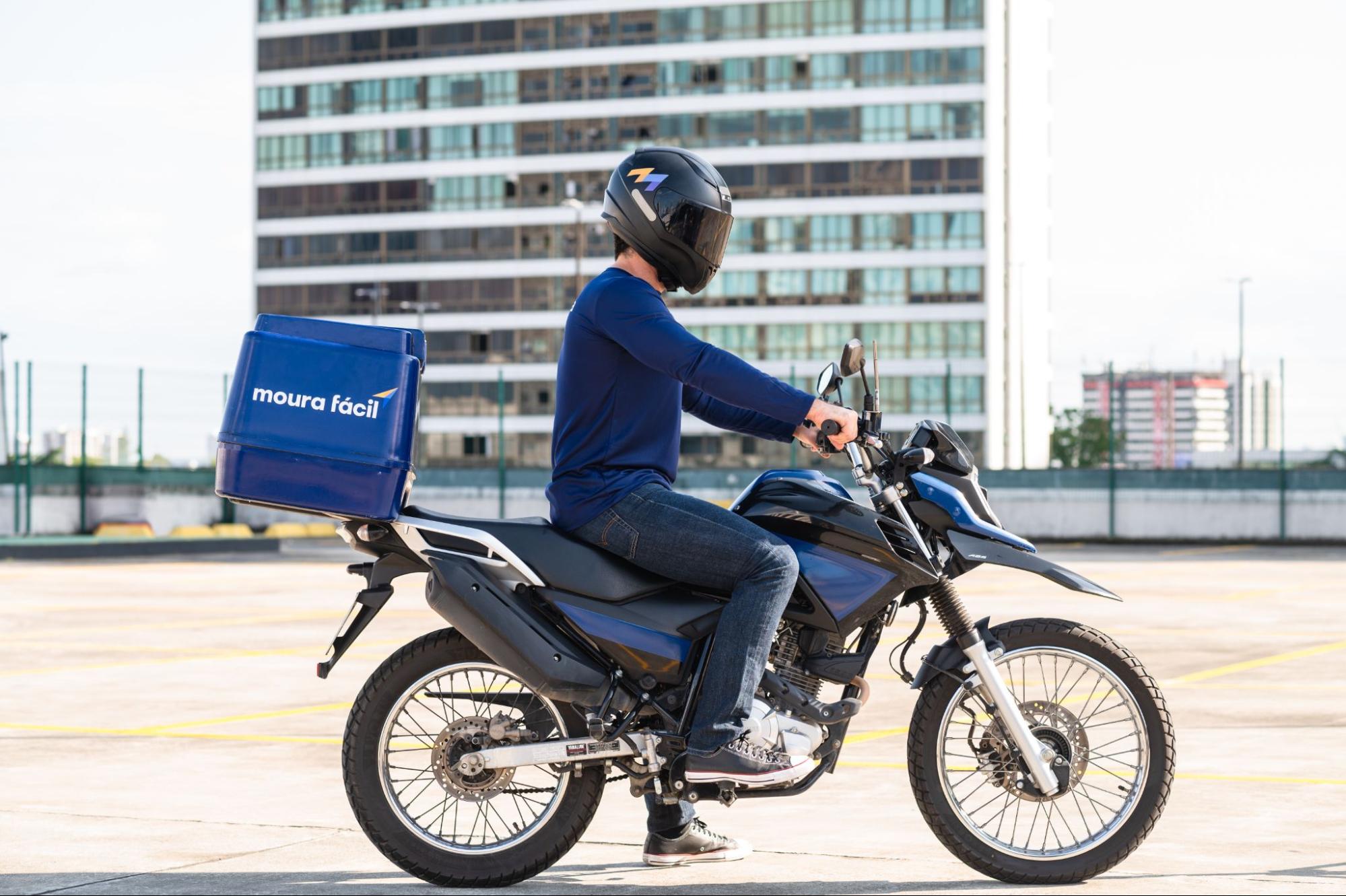 Homem de capacete pilota moto azul do Moura Fácil.