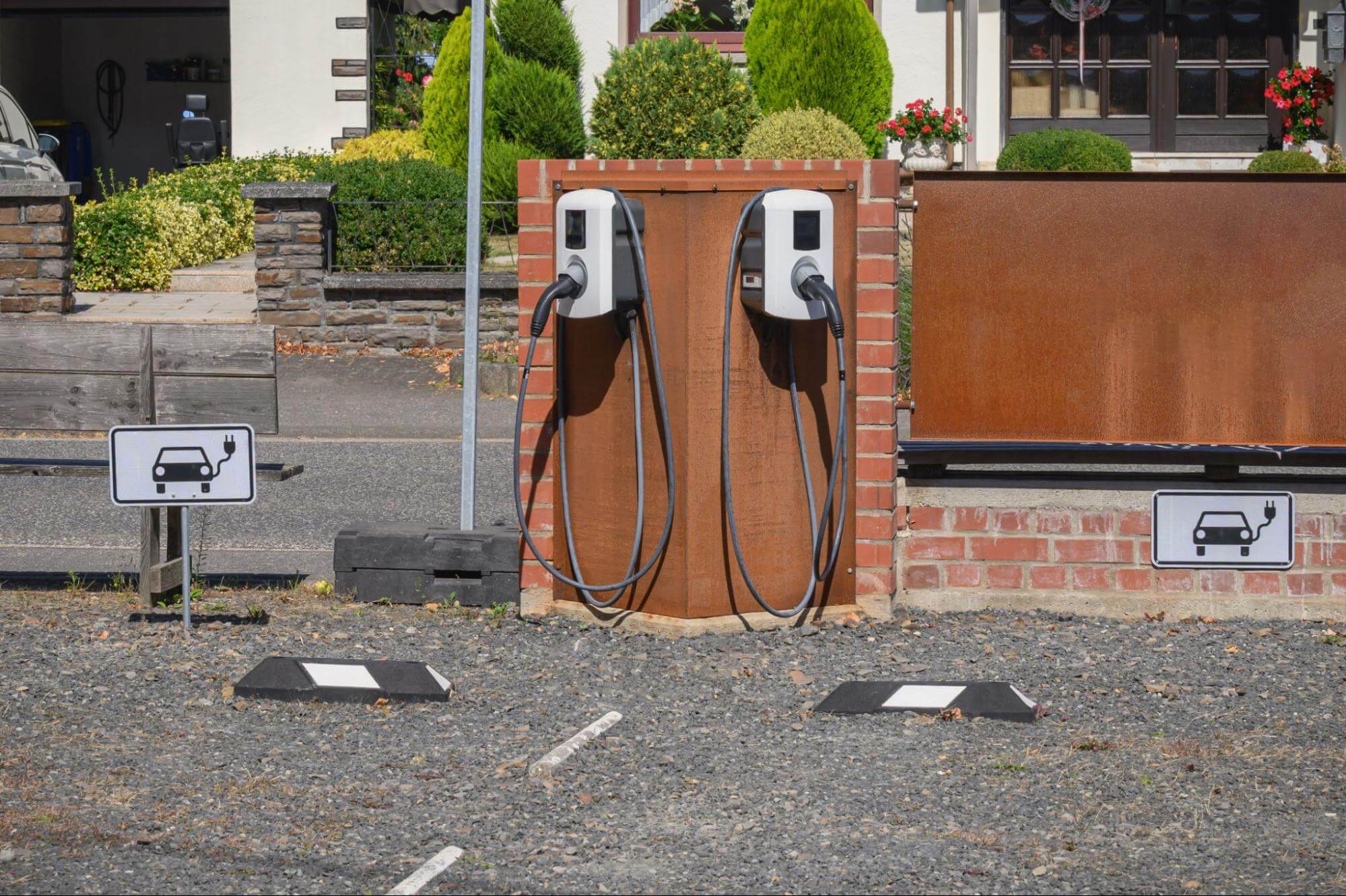 Estação de recarga com dois carregadores para carros elétricos instalados em uma estrutura de tijolos em um estacionamento.