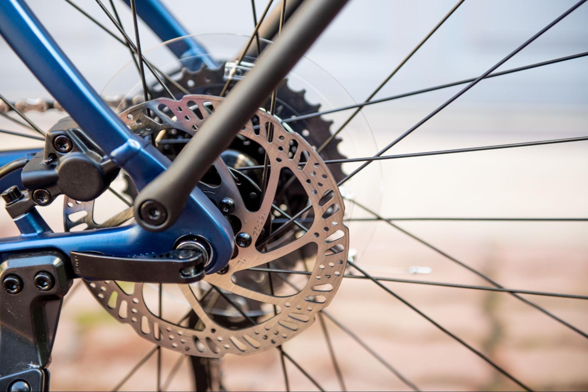 Close no freio a disco e no cassete da roda traseira de uma bicicleta azul.