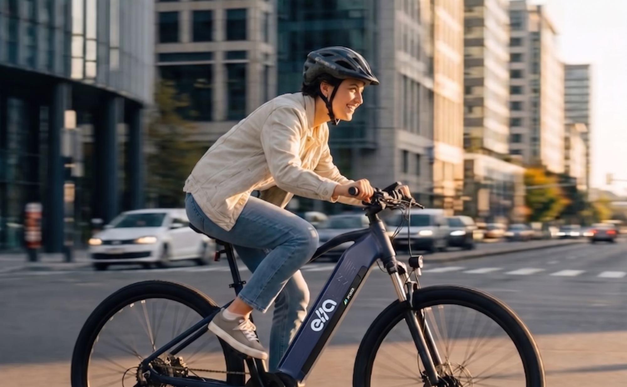 Mulher com capacete pedalando uma e-bike azul da Moura em postura inclinada para tráfego intenso em via urbana.